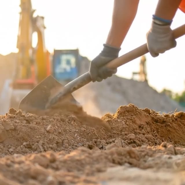 Gloved hands digging into soil with a shovel